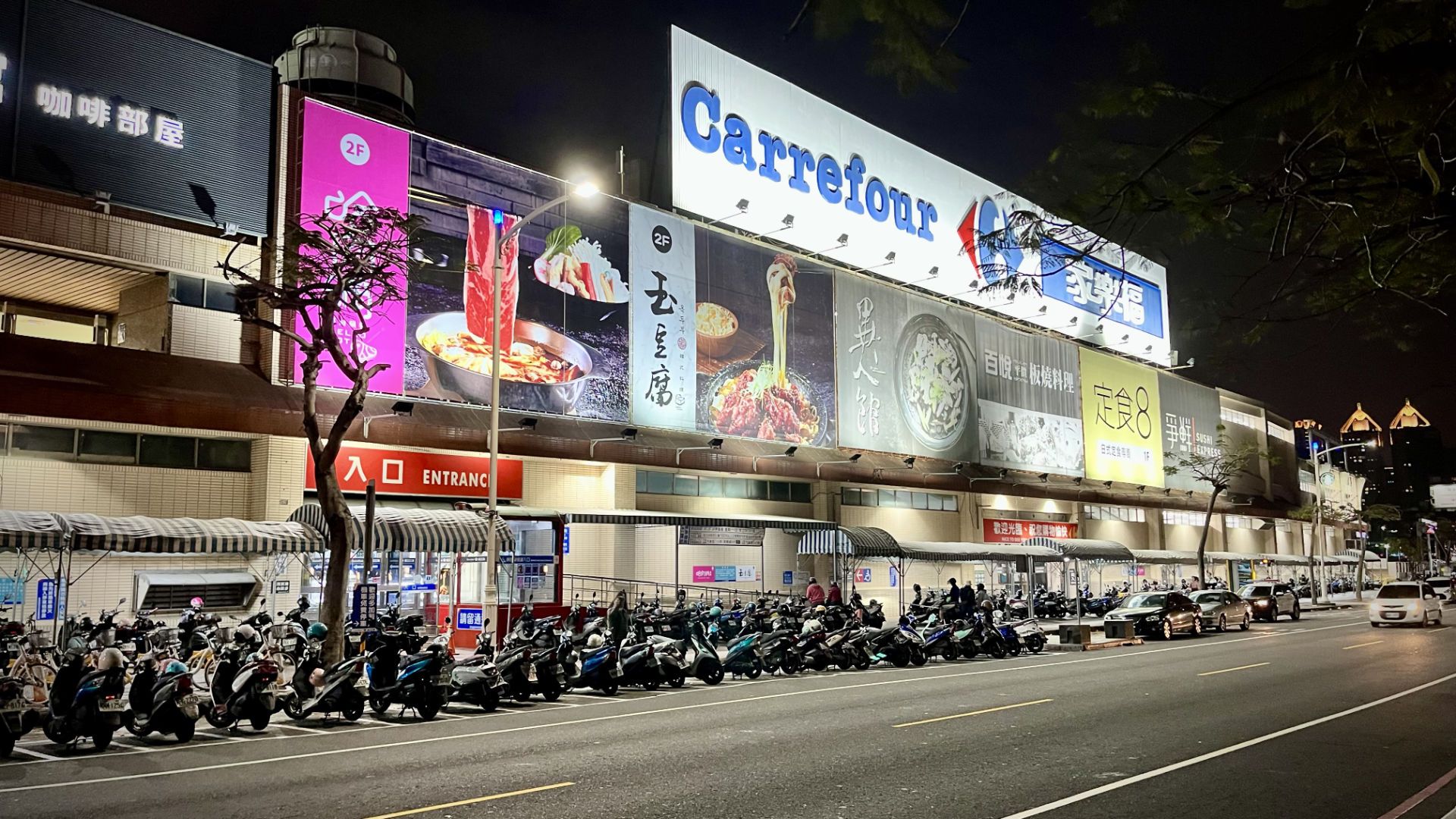 The outside of the Carrefour at Love River. Dozens of scooters are parked outside.