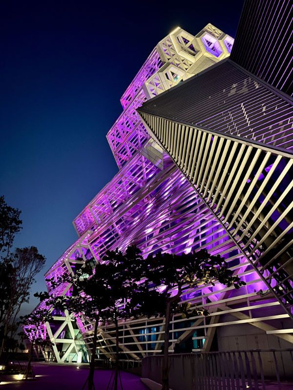 Close-up of the Kaohsiung Music Center illuminated at night, taken from a low angle.