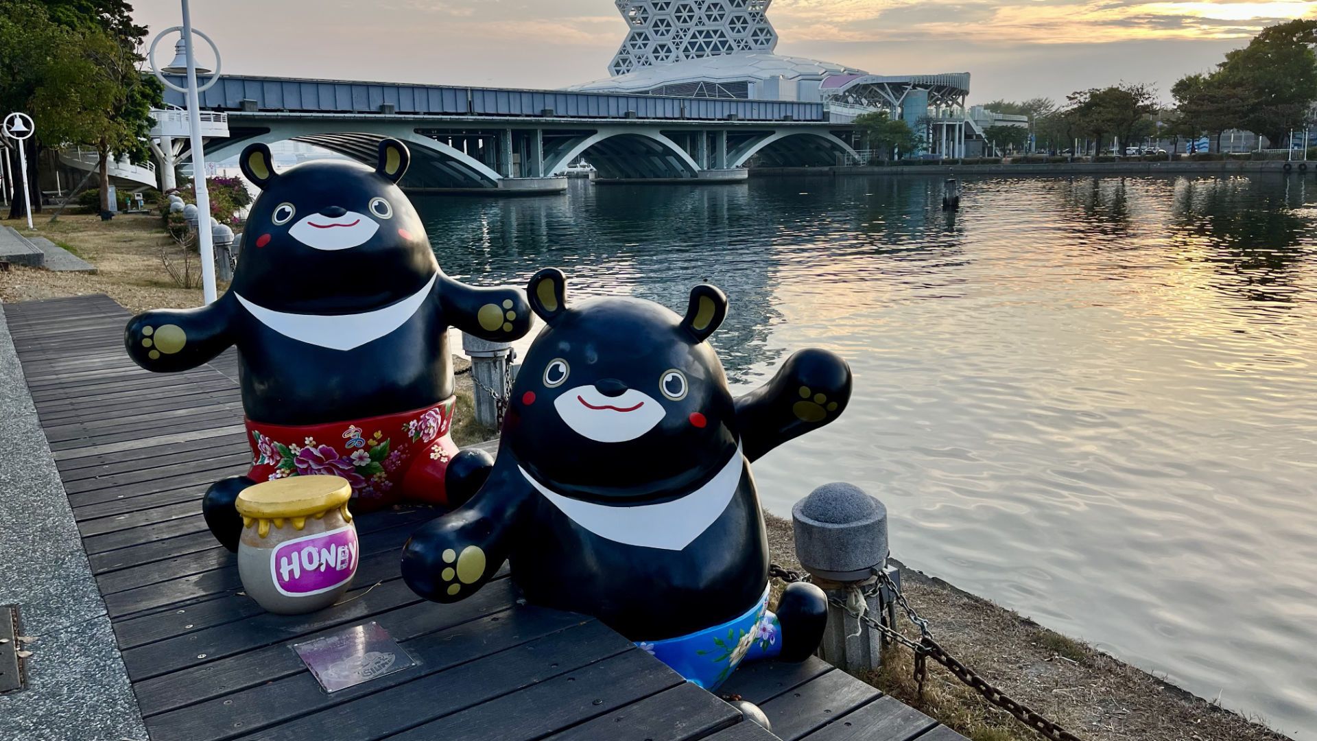 Two Formosan black bear mascots next to the river, with a large jar labeled ‘honey’.