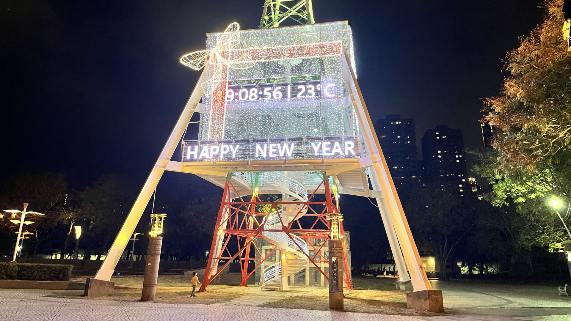 Another view of the gift-wrapped pylon, with a small child standing at the left edge, looking upwards.