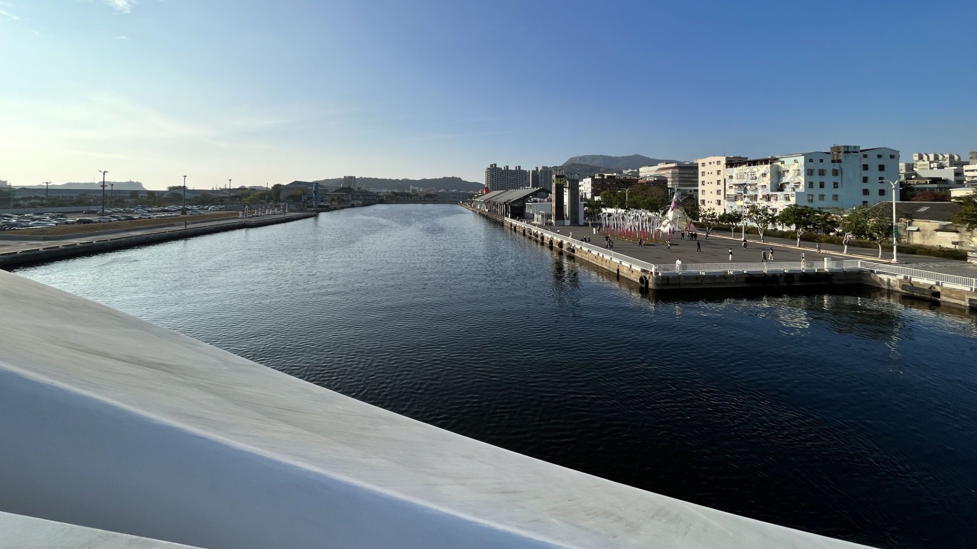 View from the bridge looking up the empty harbor, with hills in the distance.