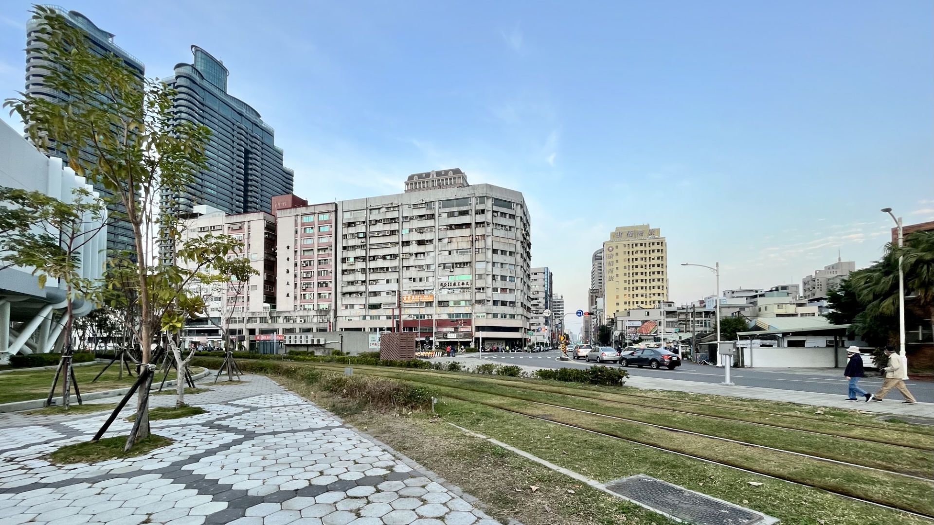 A city scene with an older, dirtier building at the center, and more modern skyscrapers in the background.