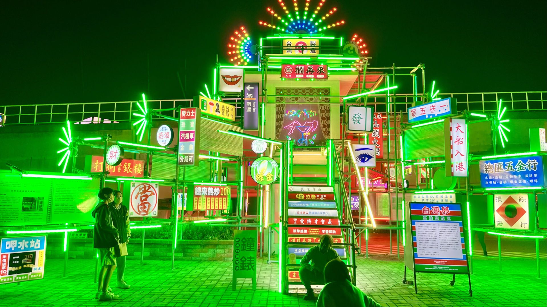 A scaffold-like structure, about 5 meters tall, brightly illuminated and covered in Chinese-language advertising.