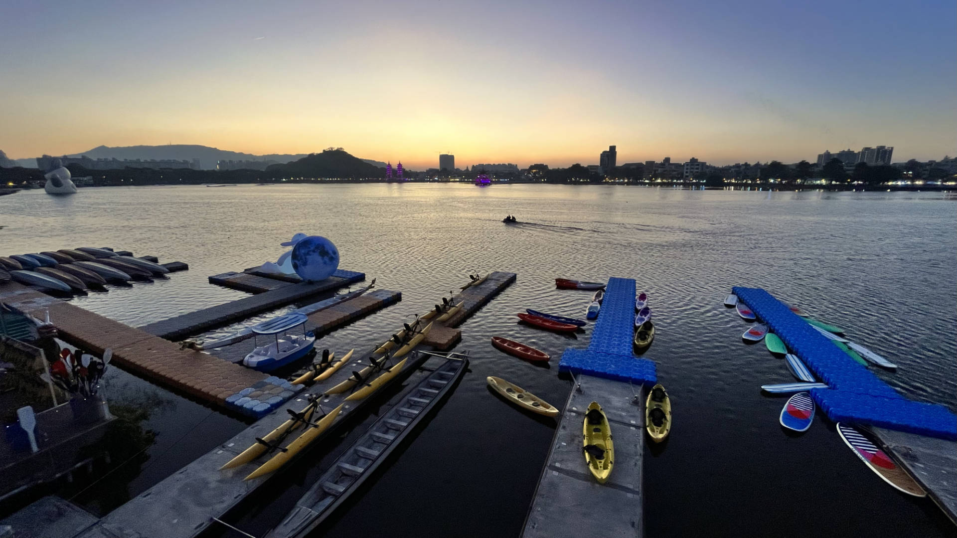 Sunset over Lotus Pond, with kayaks and dragon boats docked in the foreground.