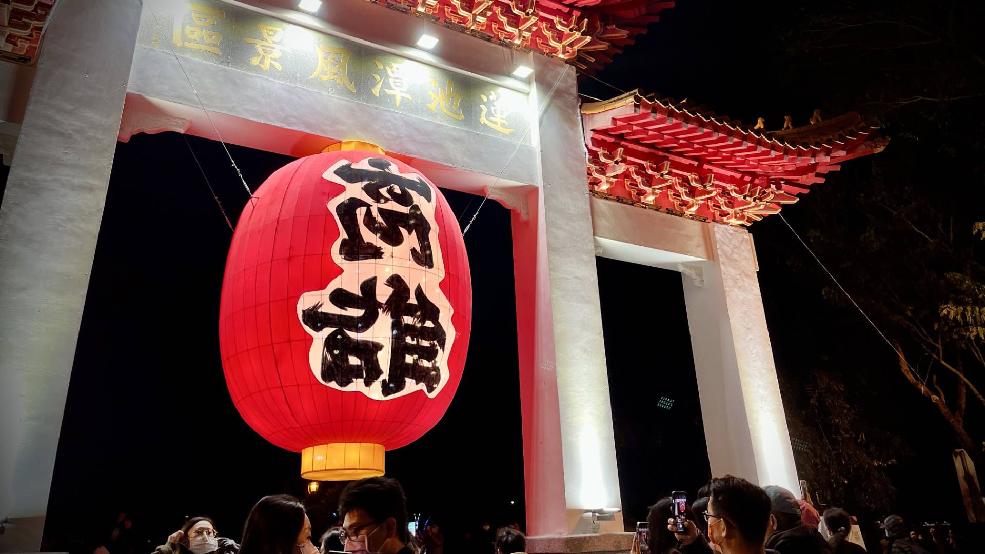 A large lantern hanging from a traditional gateway.