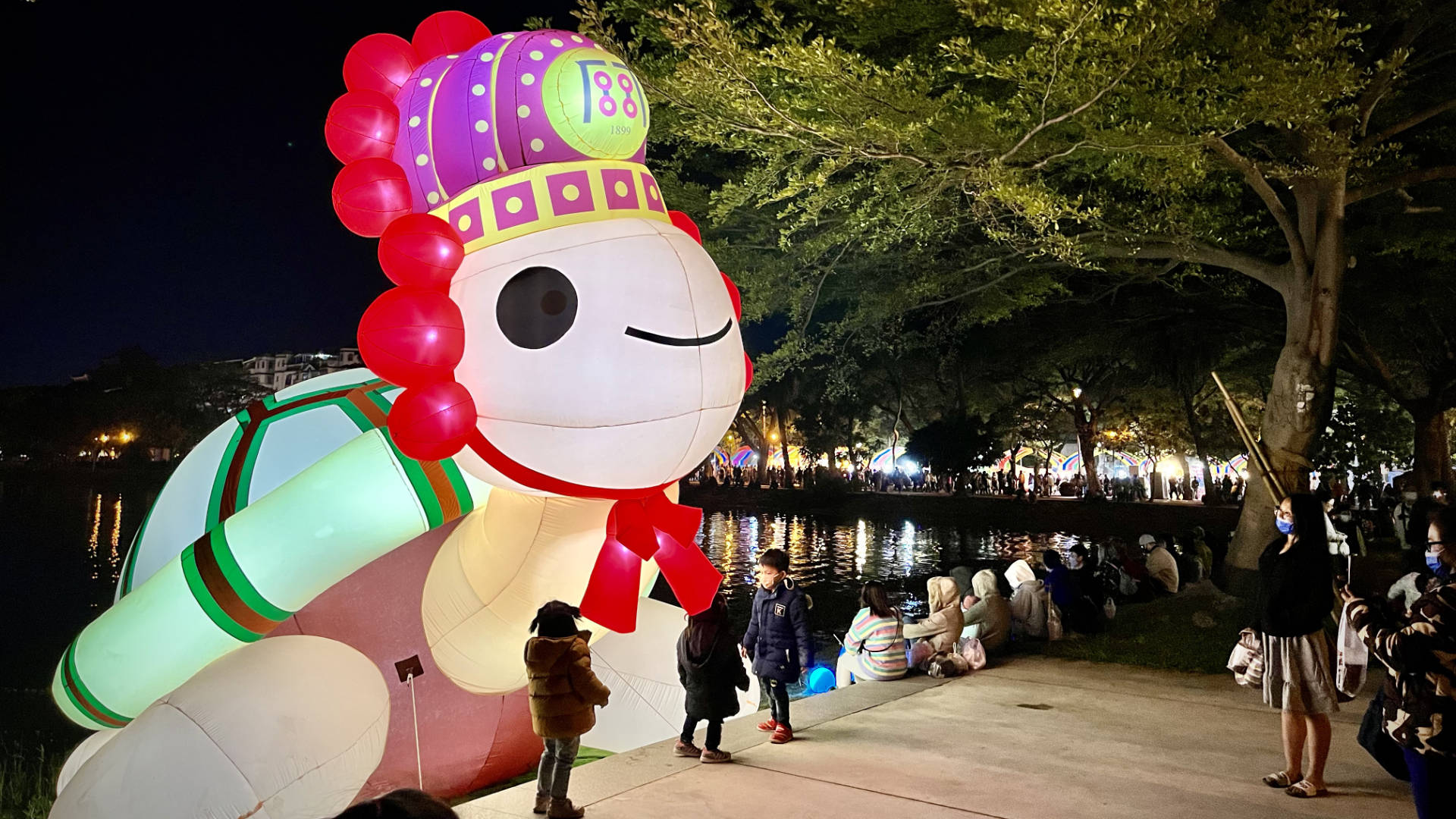A large illuminated inflatable turtle on the edge of the lake.