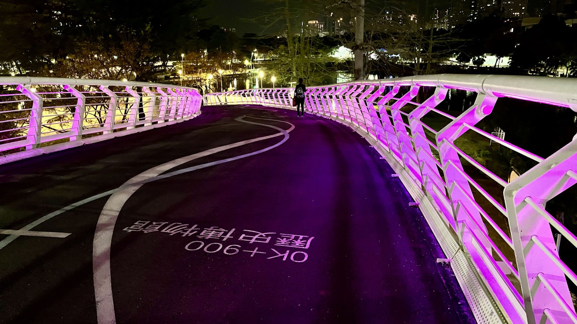 The pedestrian bridge over Bo-Ai-1st-Road, colored pink at night.