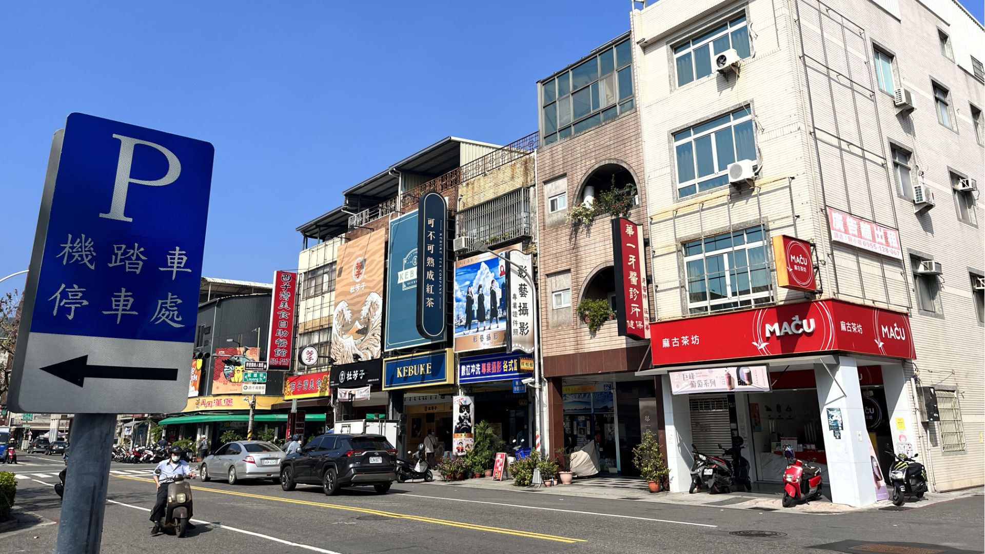 A typical two-lane street with three- and four-level buildings lining either side.