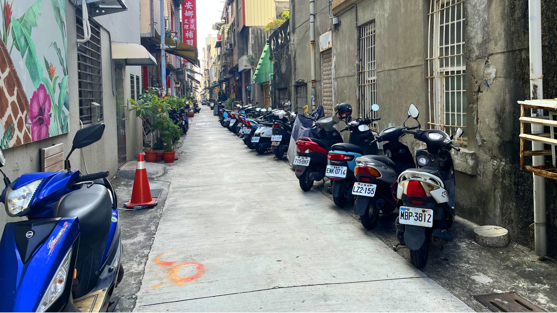 Scooters angle-parked in an alleyway.