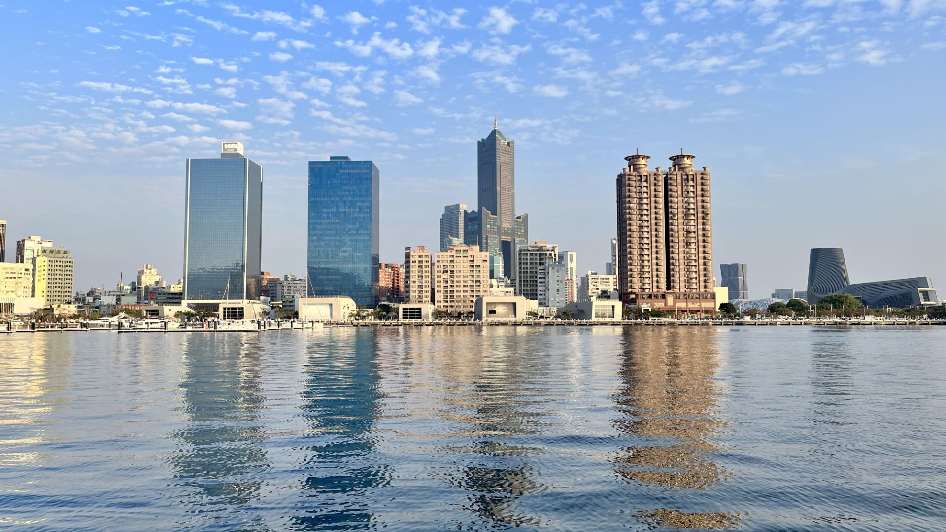 Skyscrapers reflected in the calm water of the harbor.