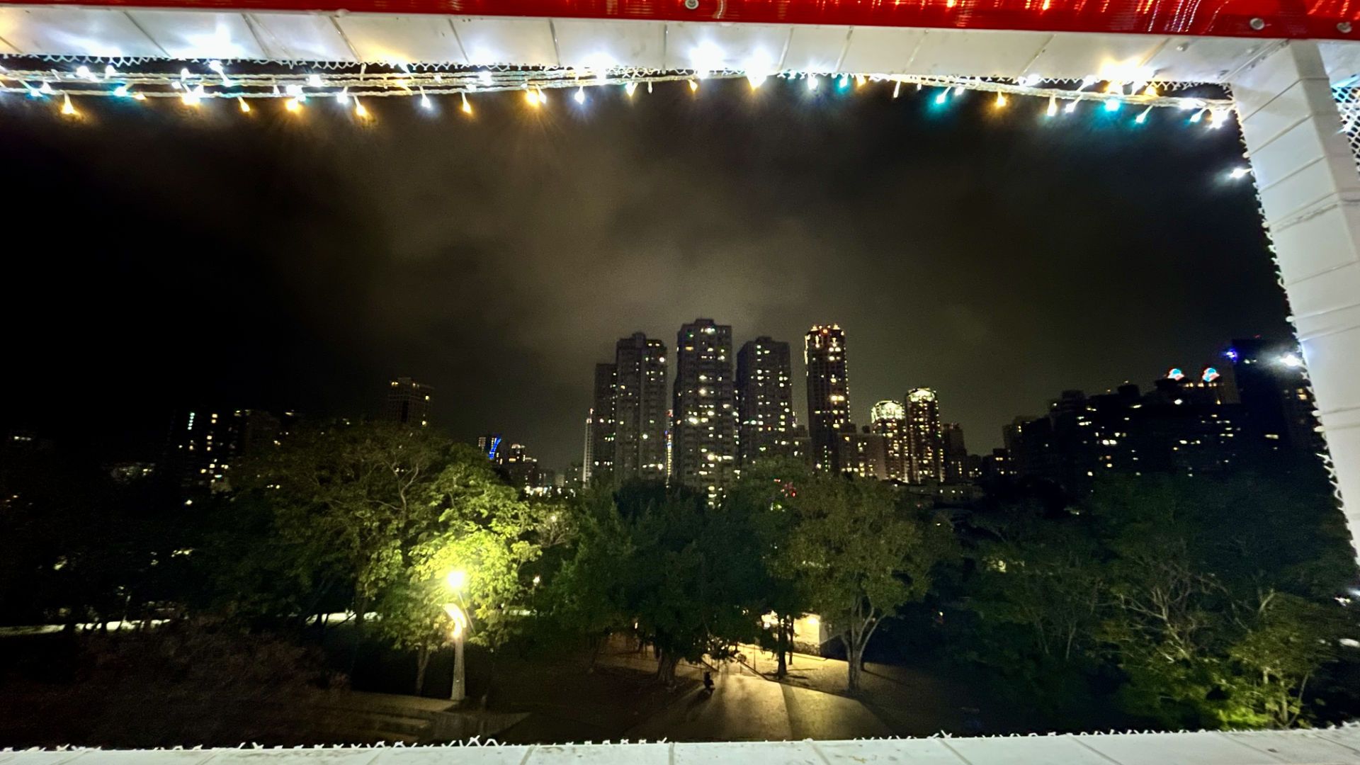 Looking out from the pylon viewing platform. A park is in the foreground, with trees and tall buildings in the distance.