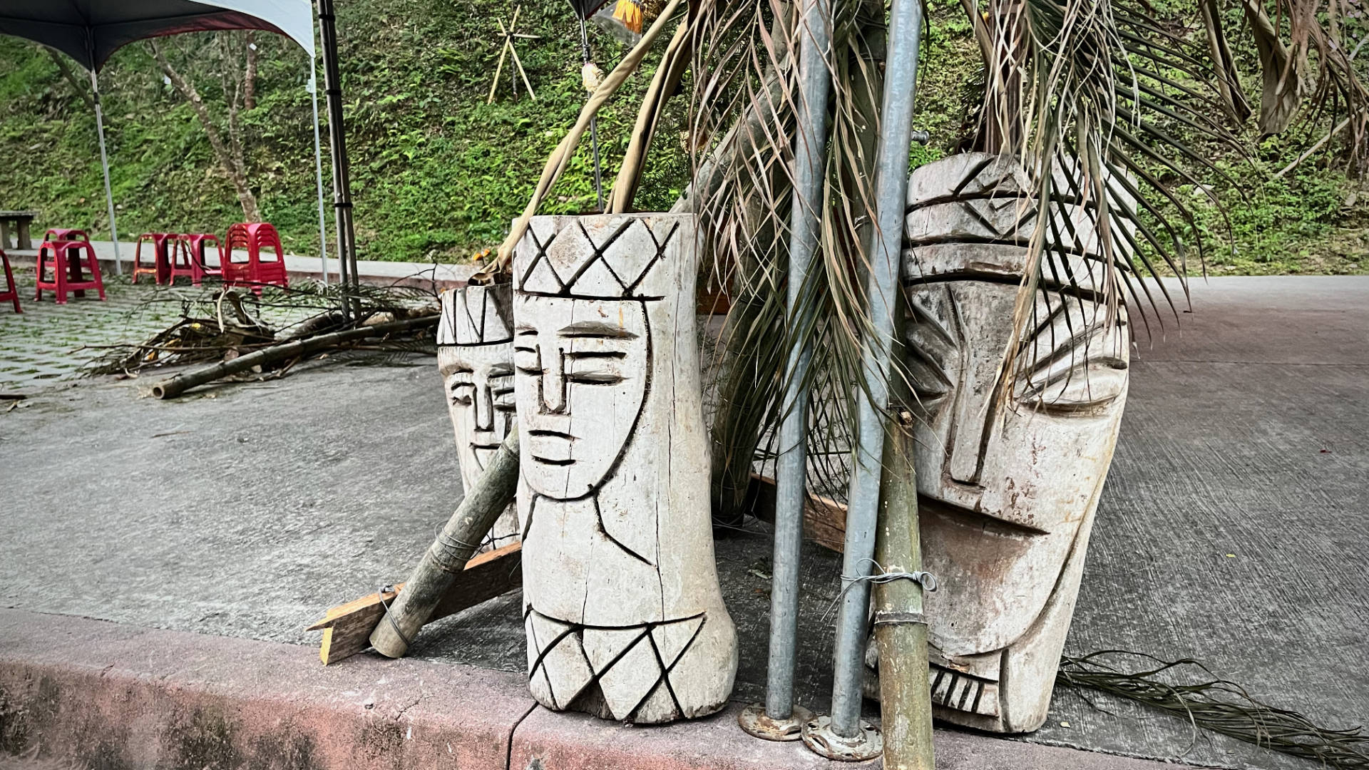 Three or four Bunun carvings, approximately 70 centimeters tall, facing the road.