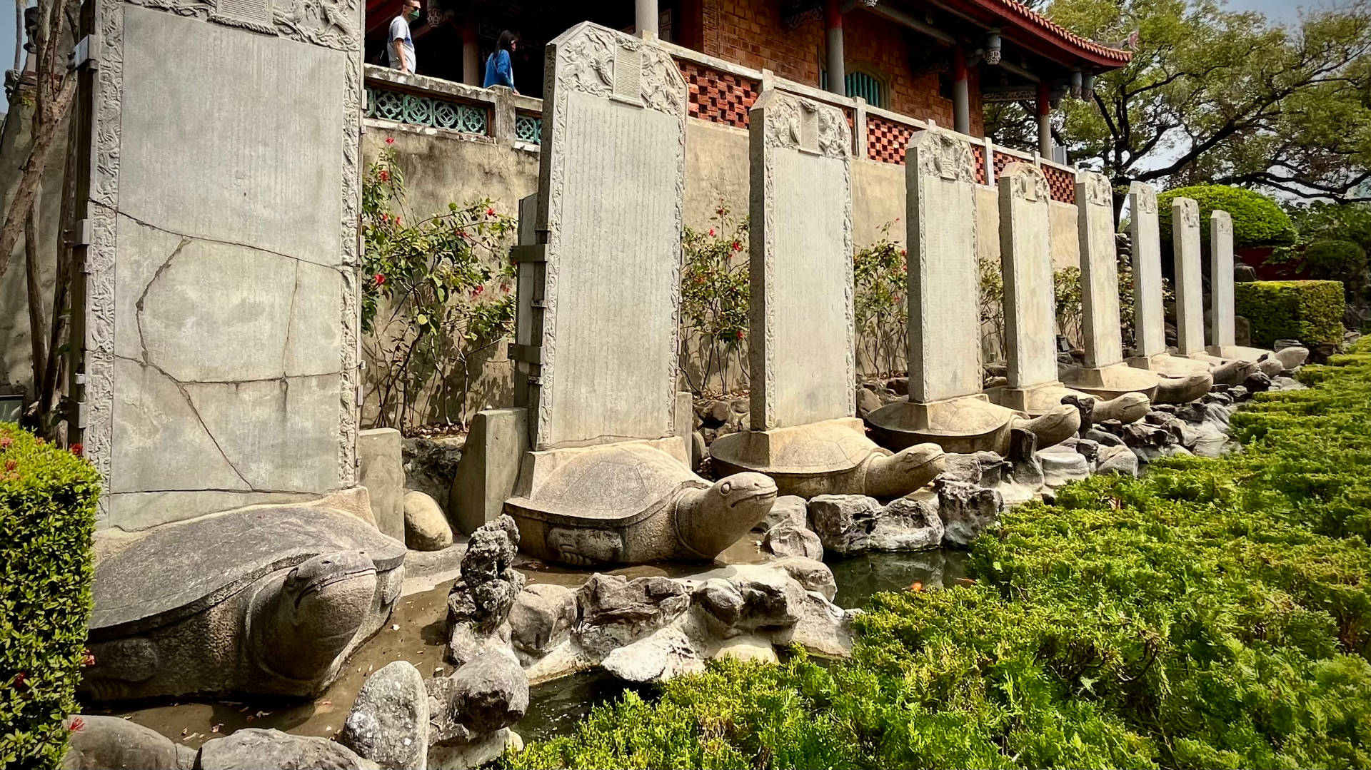 Nine statues of bixi (half-dragon, half-tortoise) creatures carrying upright stone tablets on their backs.