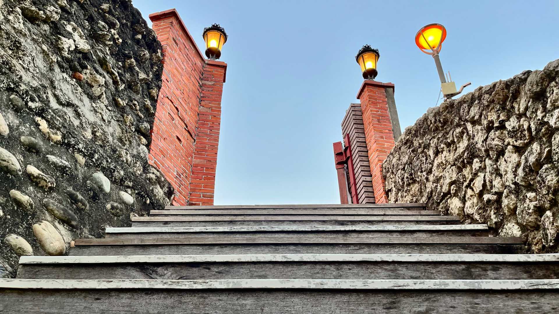 Wooden steps in the foreground lead to an open date, bordered by red brick pillars.