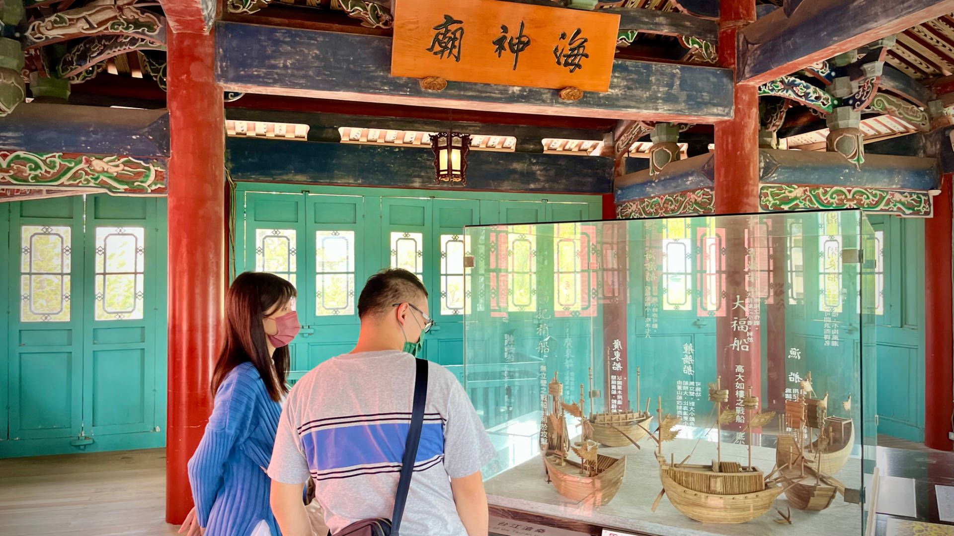 Inside the top floor of Chihkan Tower. Two people are looking at wooden models of historic ships in a glass case.