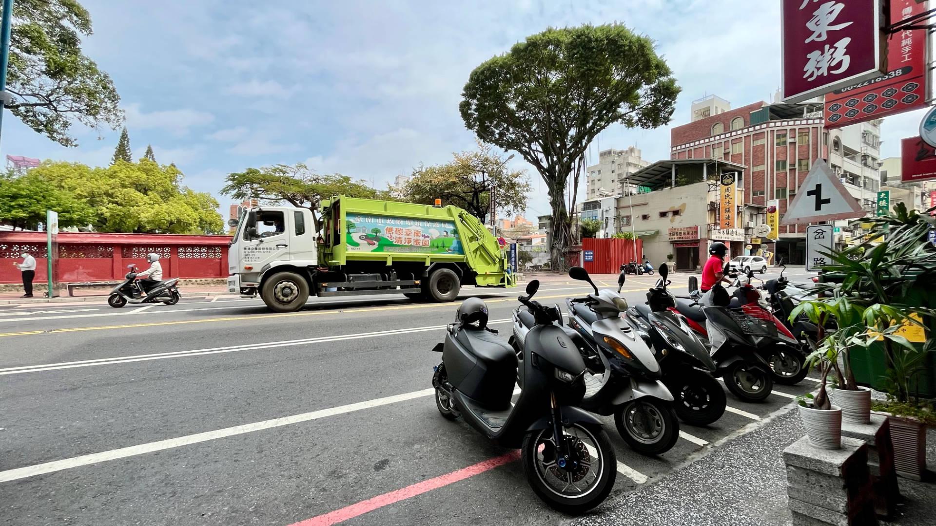 Scooters parked alongside a road in Tainan. A historic-looking wall is visible on the far side of the road.