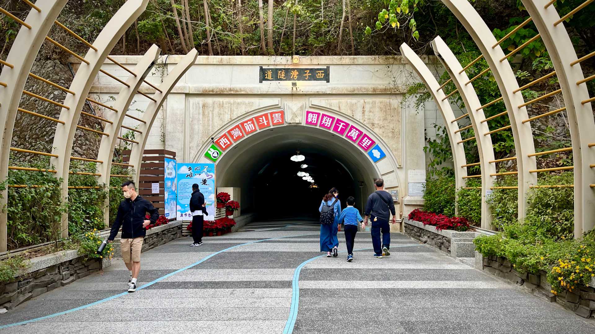 The entrance to Sizihwan Tunnel, with three pedestrians about to enter and two walking out.