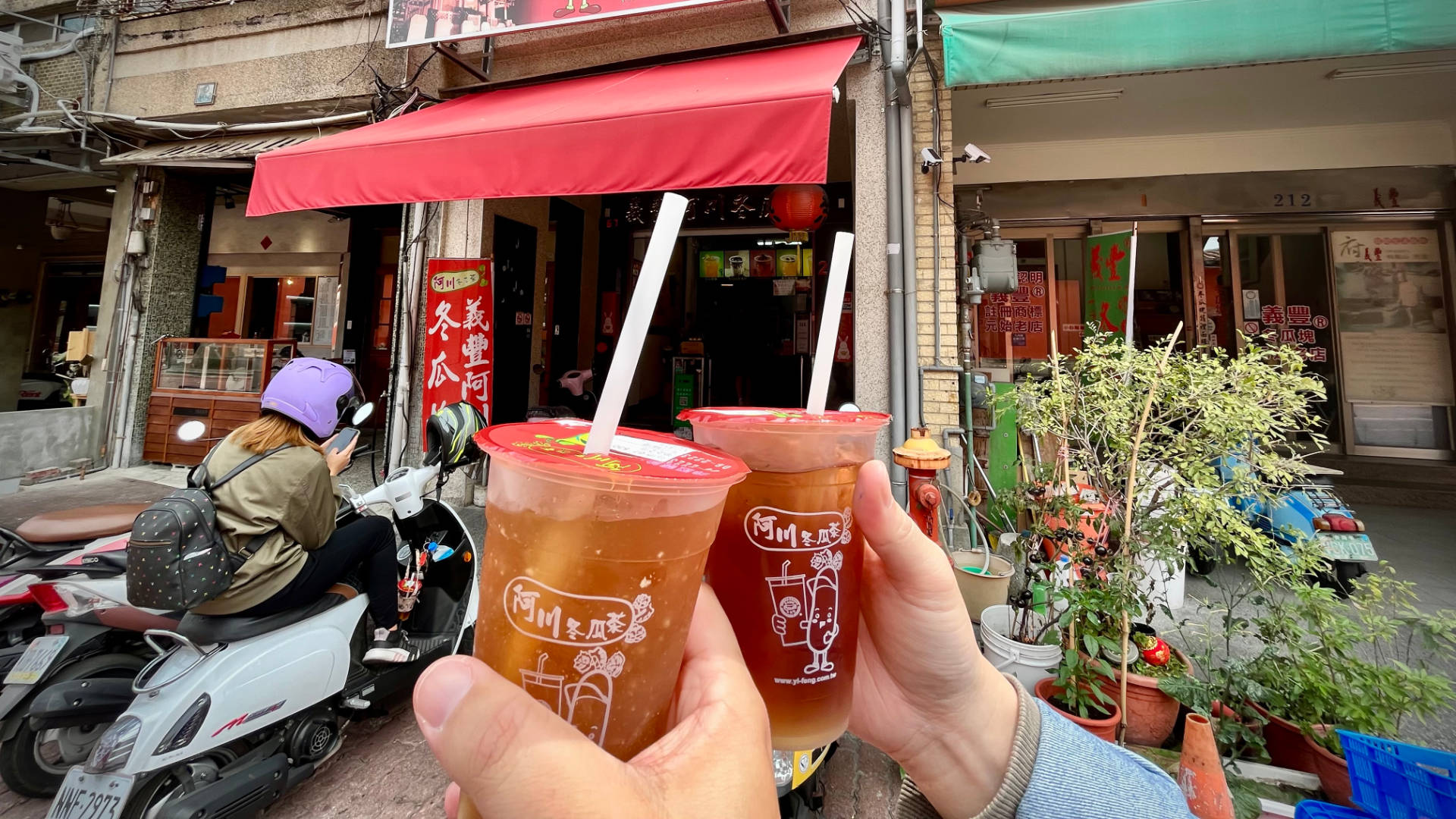 Two hands holding two cups of iced tea.