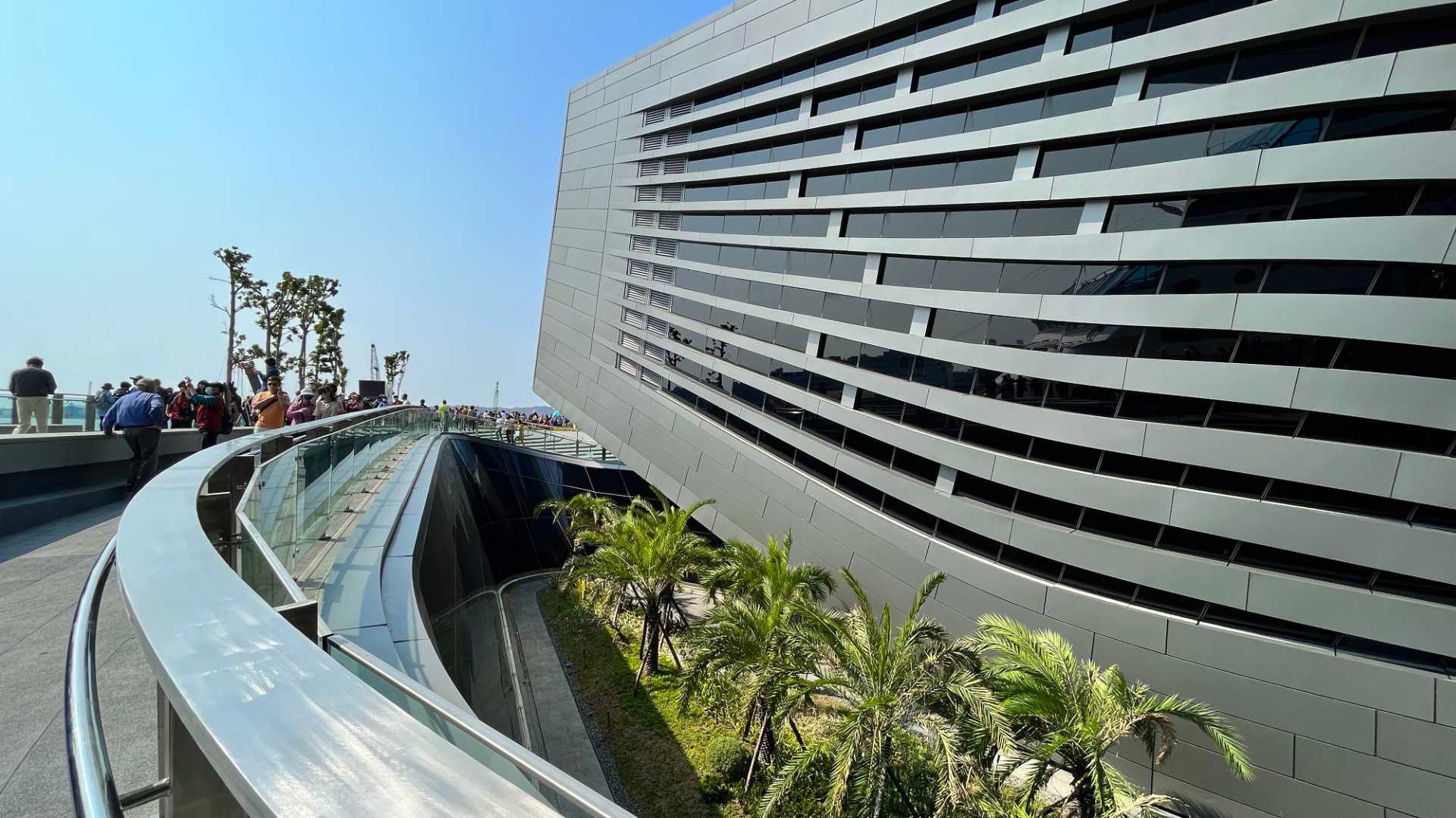 Looking along the viewing deck, the main part of the building is on the right and a garden of palm trees is visible one level lower.