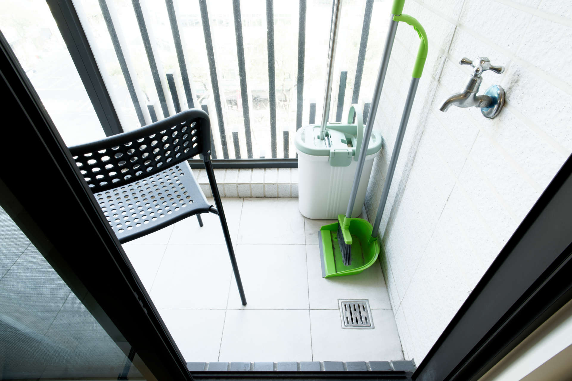 A chair, mop, and broom on the balcony.