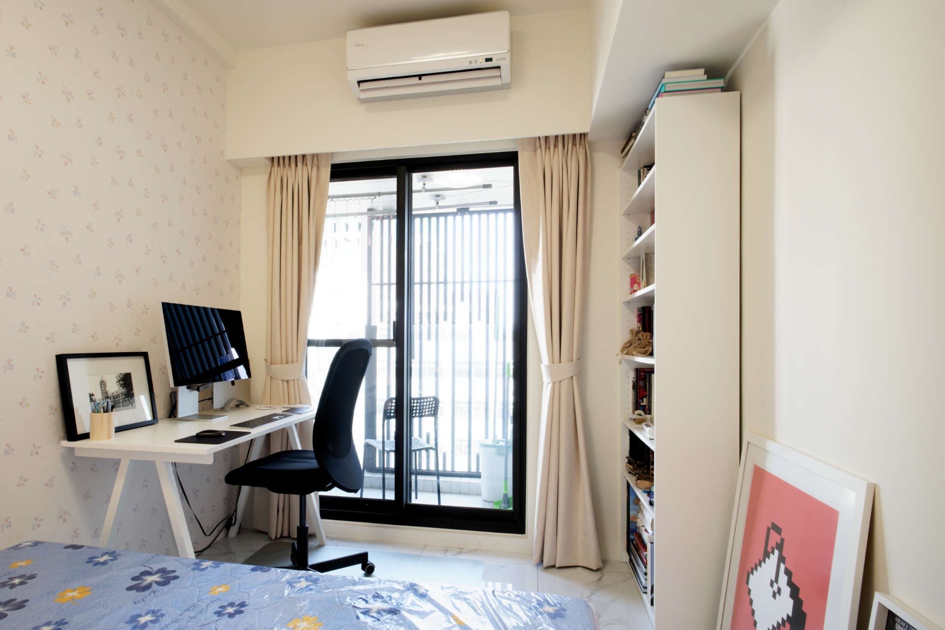 A bedroom with double bed, office furniture, and a chair on the balcony outside.