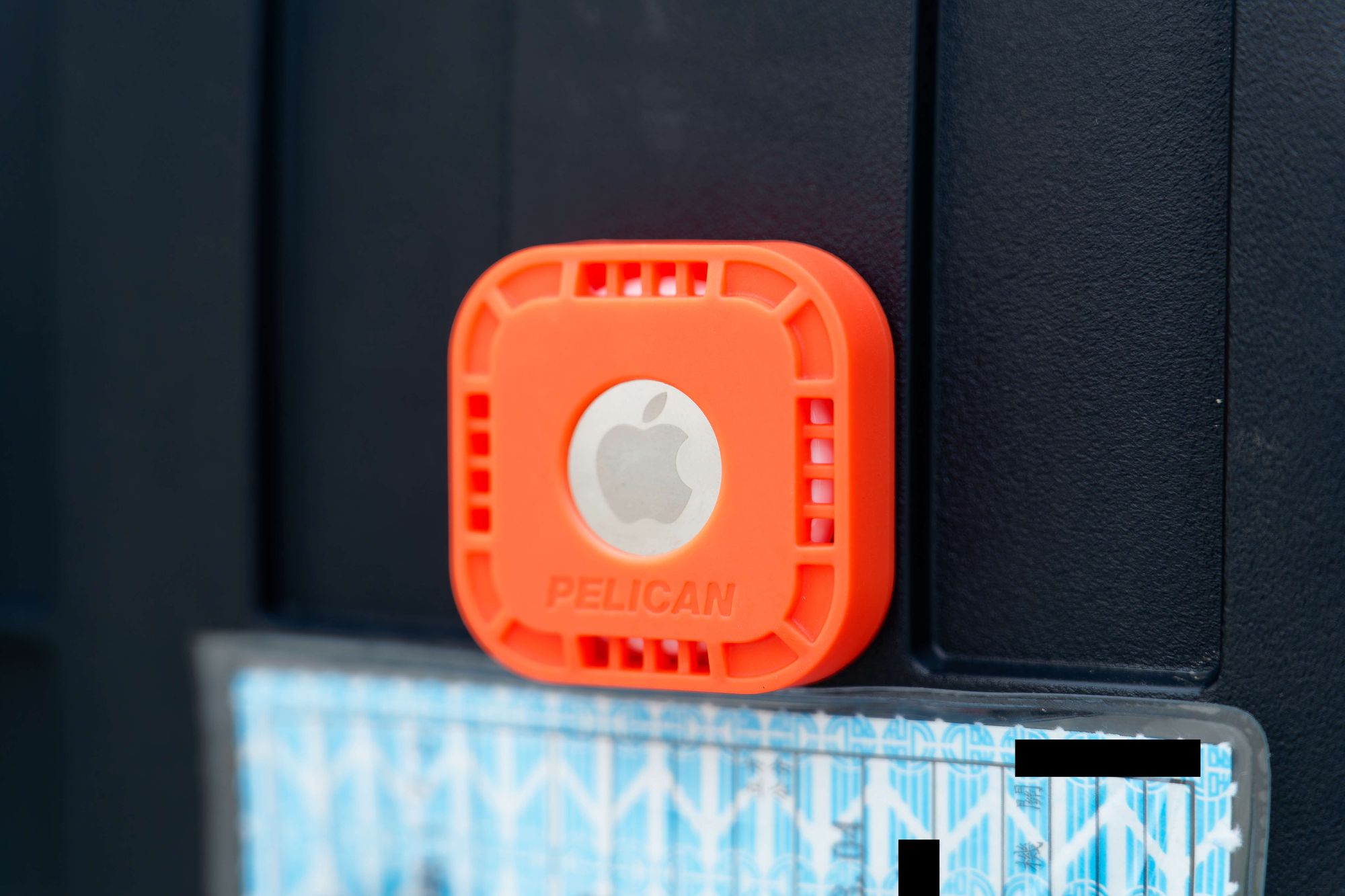 An Apple AirTag inside a Pelican case, mounted to the underside of a scooter seat.