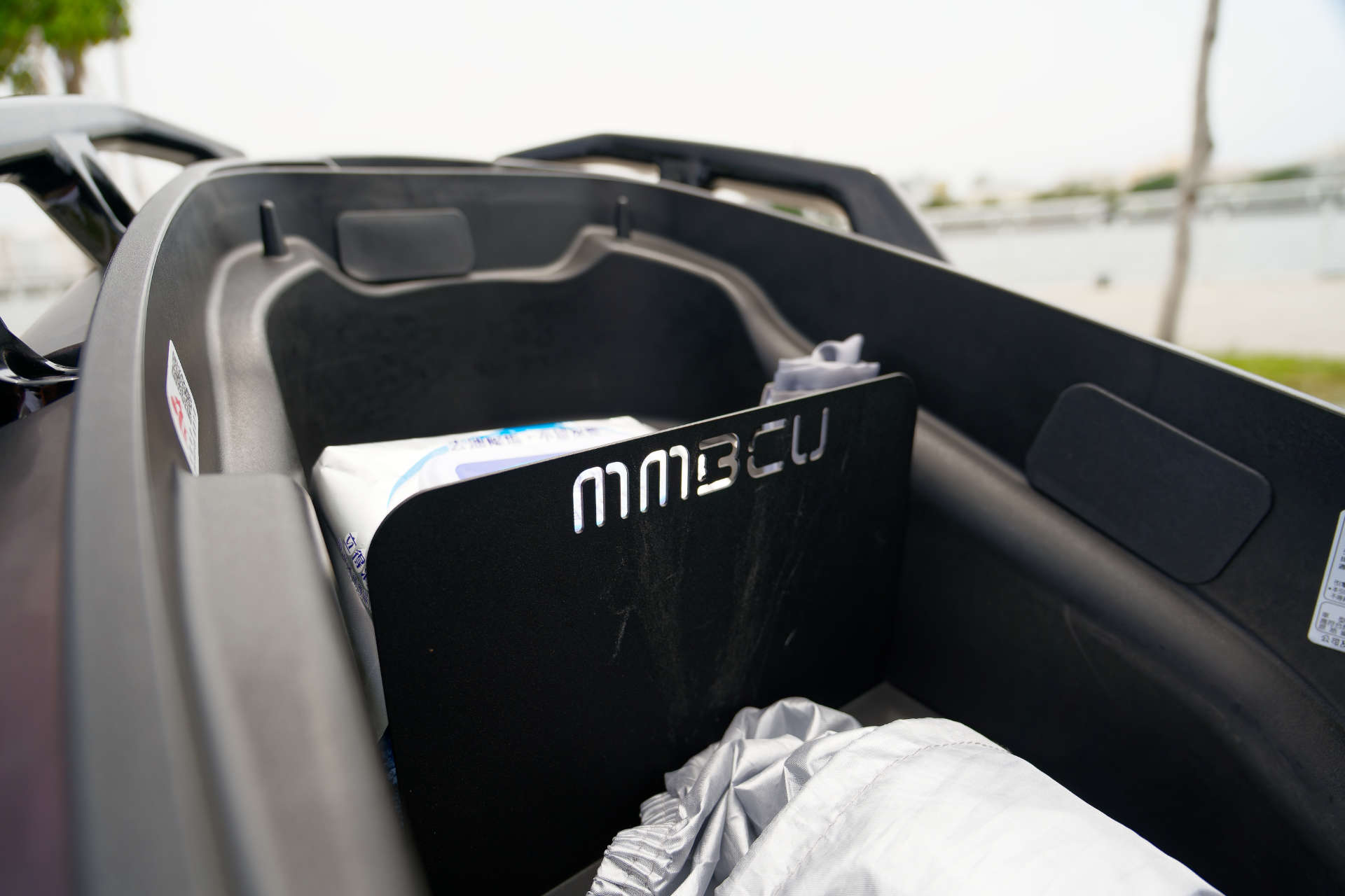 An MMBCU-branded storage divider mounted on an SYM MMBCU scooter.