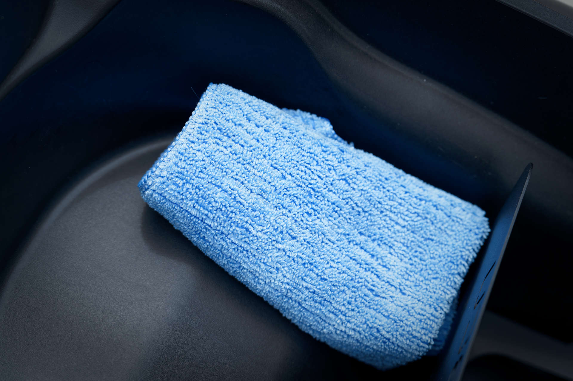 Blue cleaning cloth in an under-seat scooter storage area.