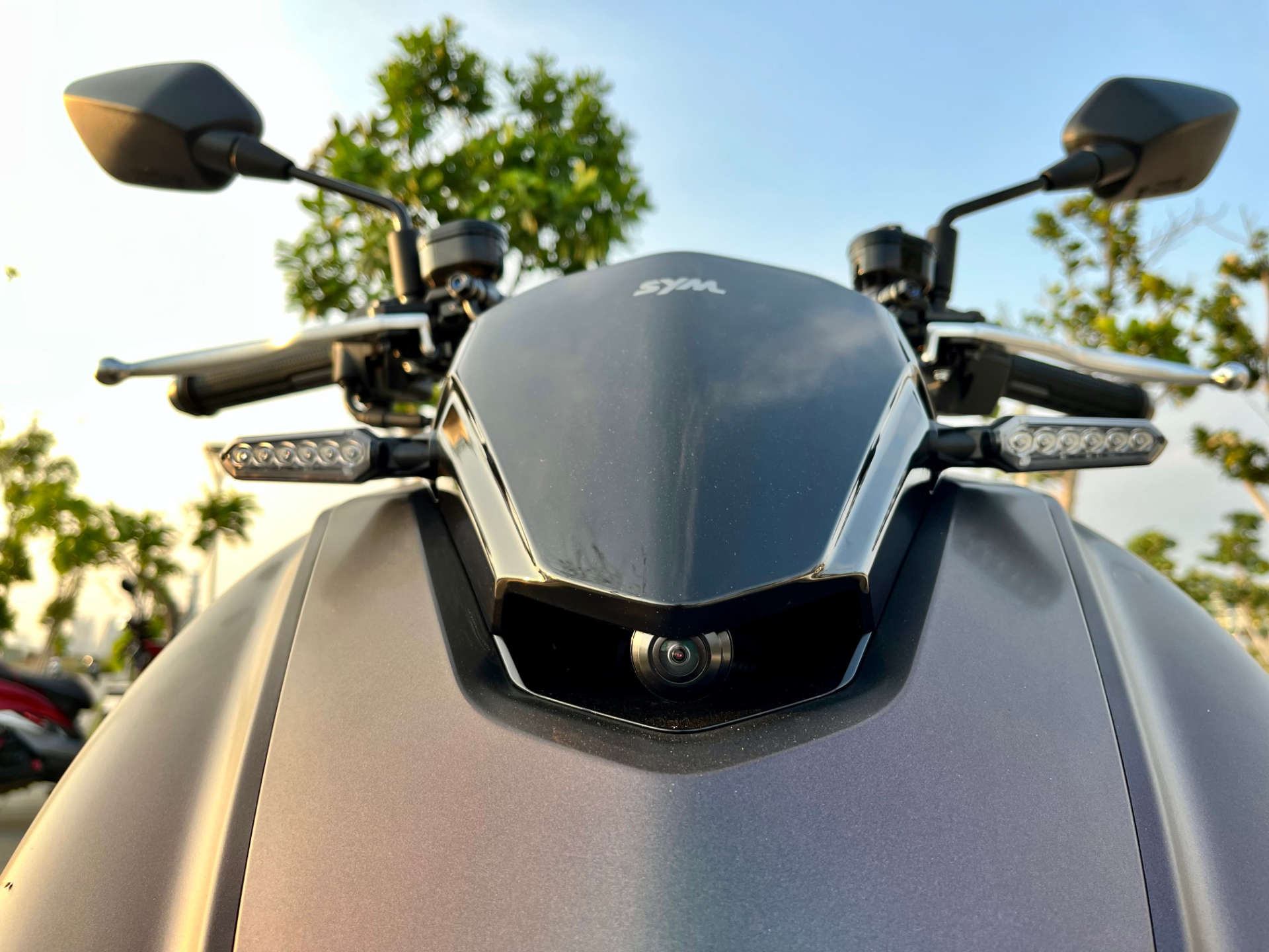 Close-up of a front-facing dashcam camera installed on an SYM MMBCU scooter.