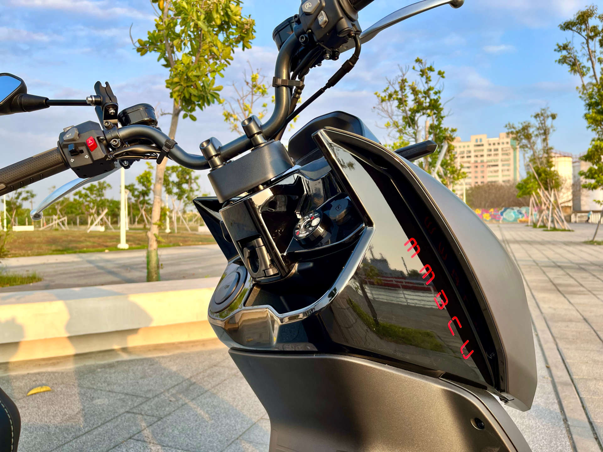 Close-up of the MMBCU branding printed on the side of the scooter.