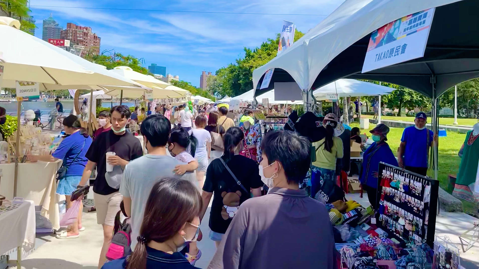 People walking through a crowded outdoor market alongside Love River in Kaoshiung.