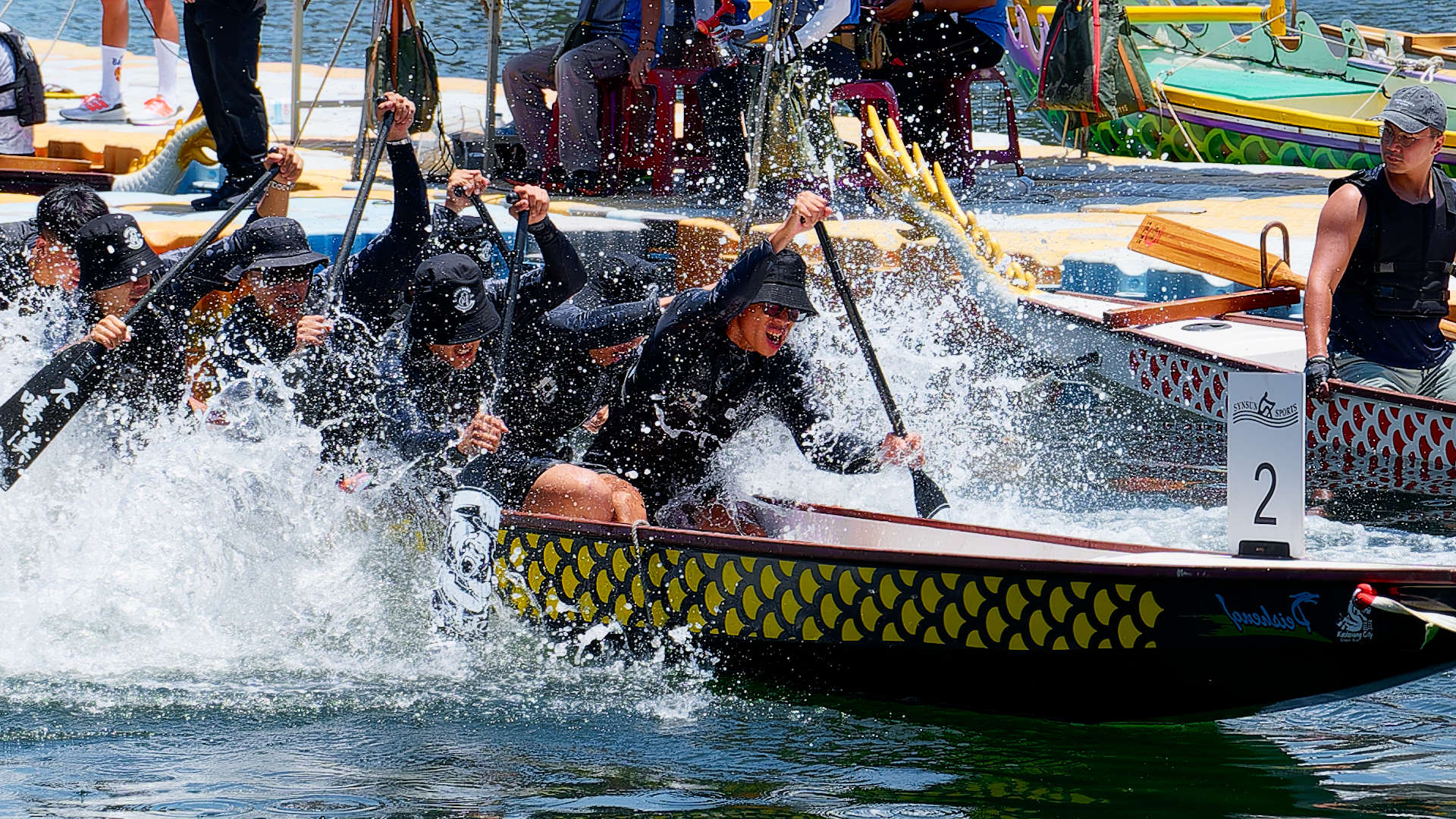 Close-up of paddlers in a dragon boat tug-of-war competition in Kaohsiung, Taiwan. Many of the paddlers are obscured by splashing water.