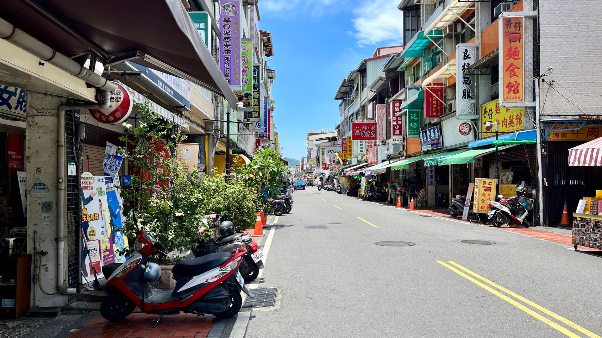 Qishan Old Street, with scooters parked in the foreground and three-story buildings lining either the side. The road is almost empty, with only one car visible in the distance.