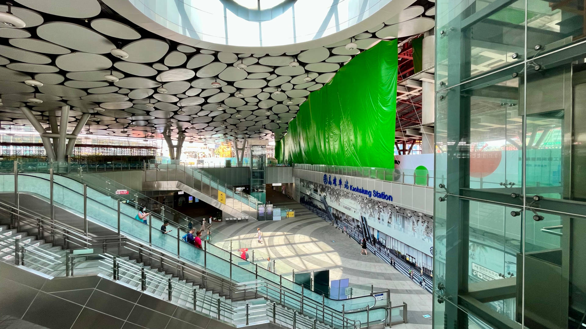 The central hall of Kaohsiung Main Station, half-blocked by temporary walls and a tarpaulin. Construction is occurring in the background.