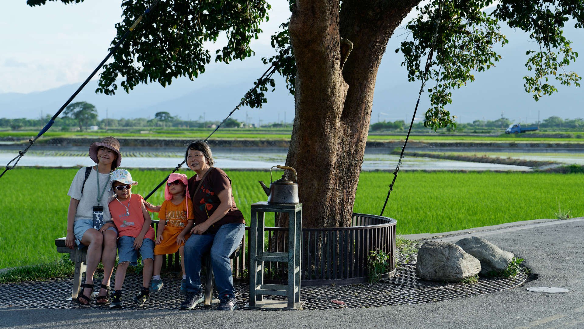 Two adults and two children pose for a photo under a tree. They are looking off-camera.