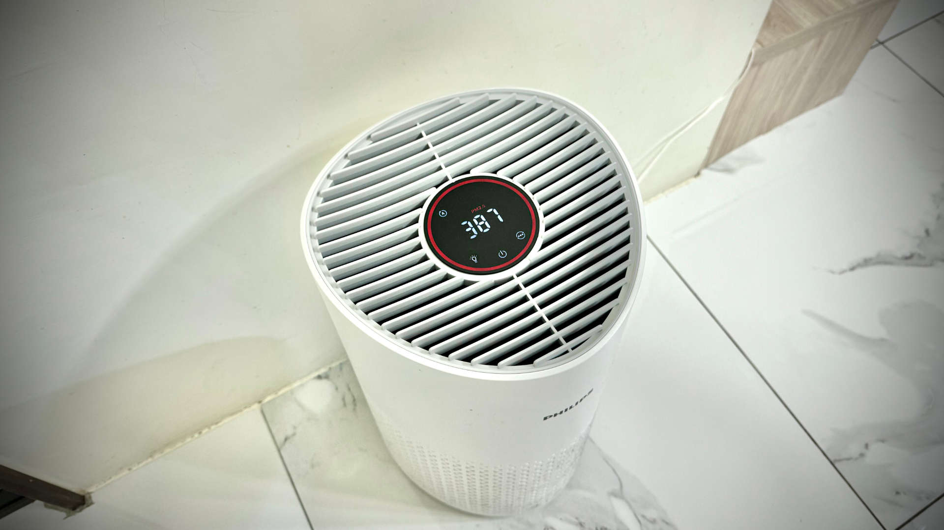 An air purifier. The screen on the purifier shows 387 PM2.5, with a red color indicating hazardous concentrations of particulate matter.