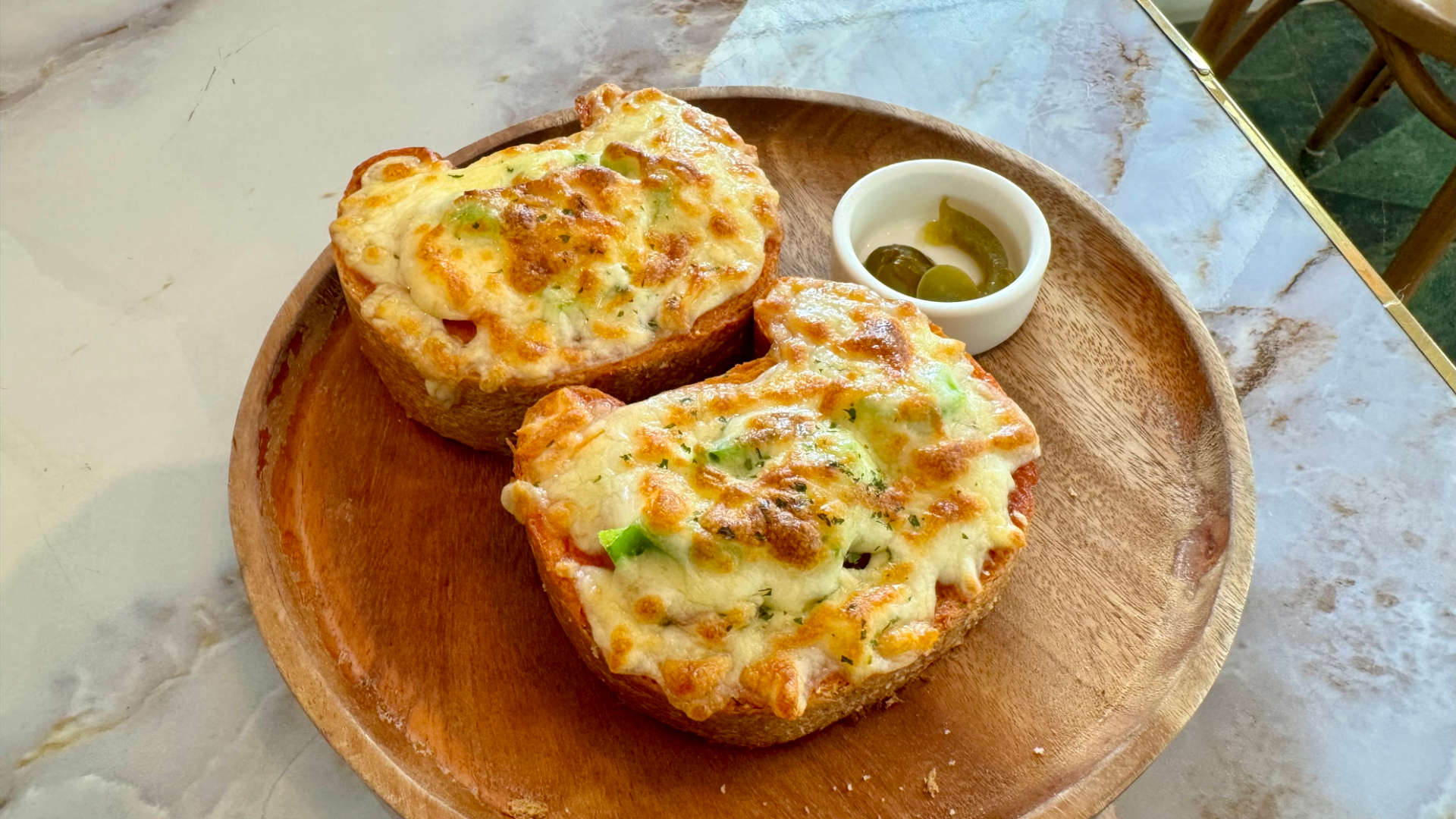 Two slices of thick toast covered in cheese. The slices of toast are in the shape of a cat’s head.