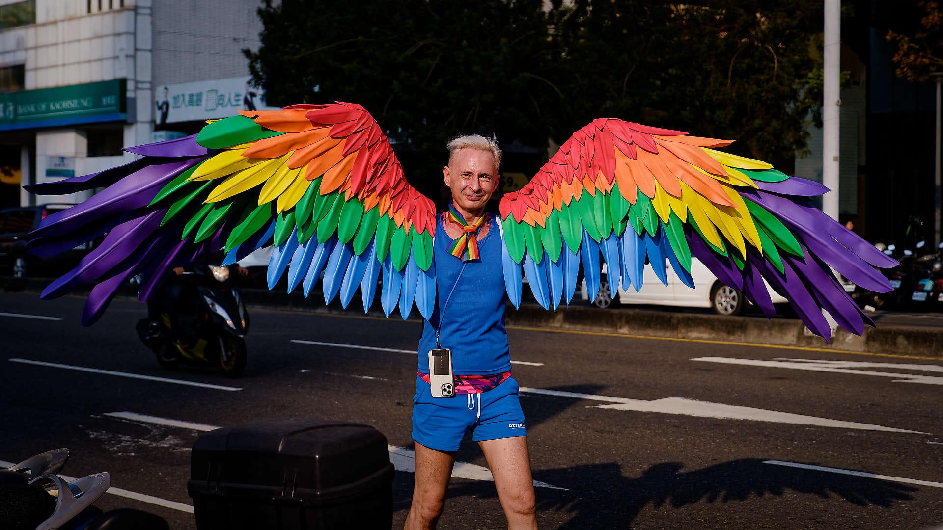 Person wearing colorful outstretched feathered wings.