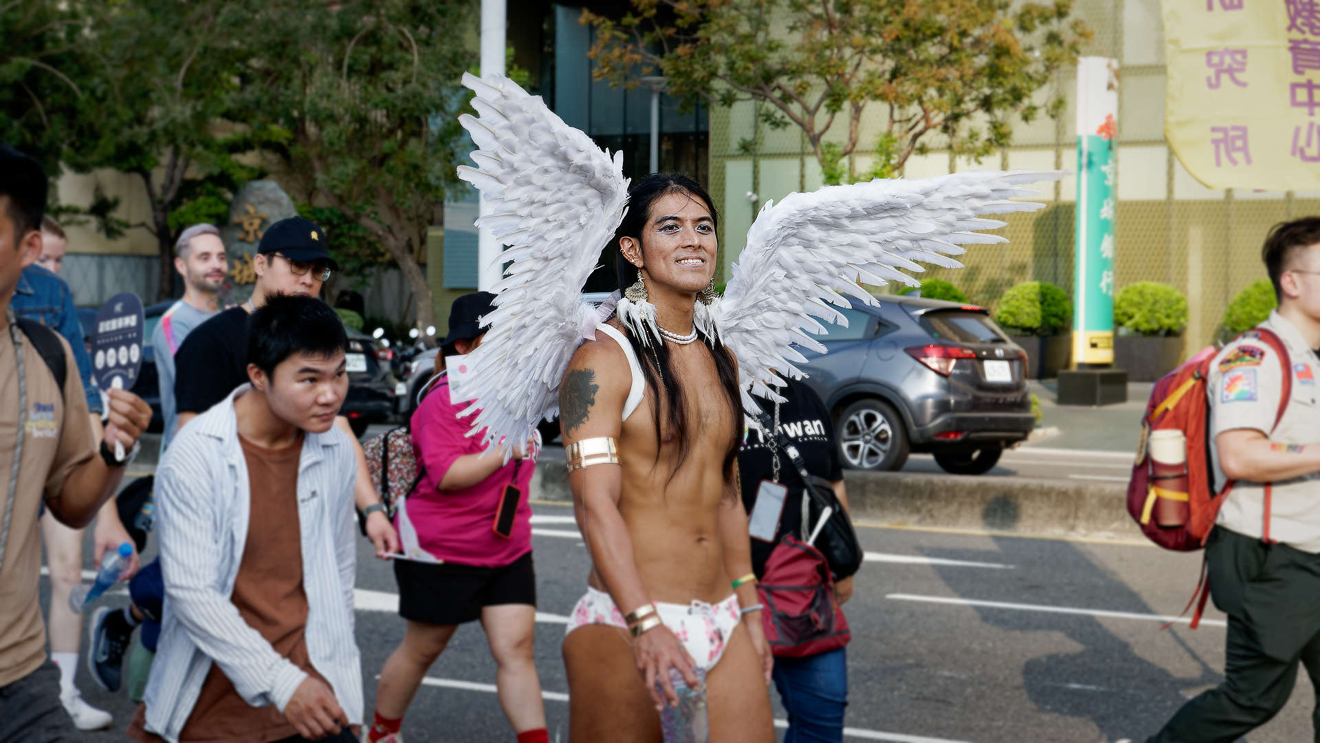 Person with large feathered wings, walking in the Kaohsiung Pride parade.