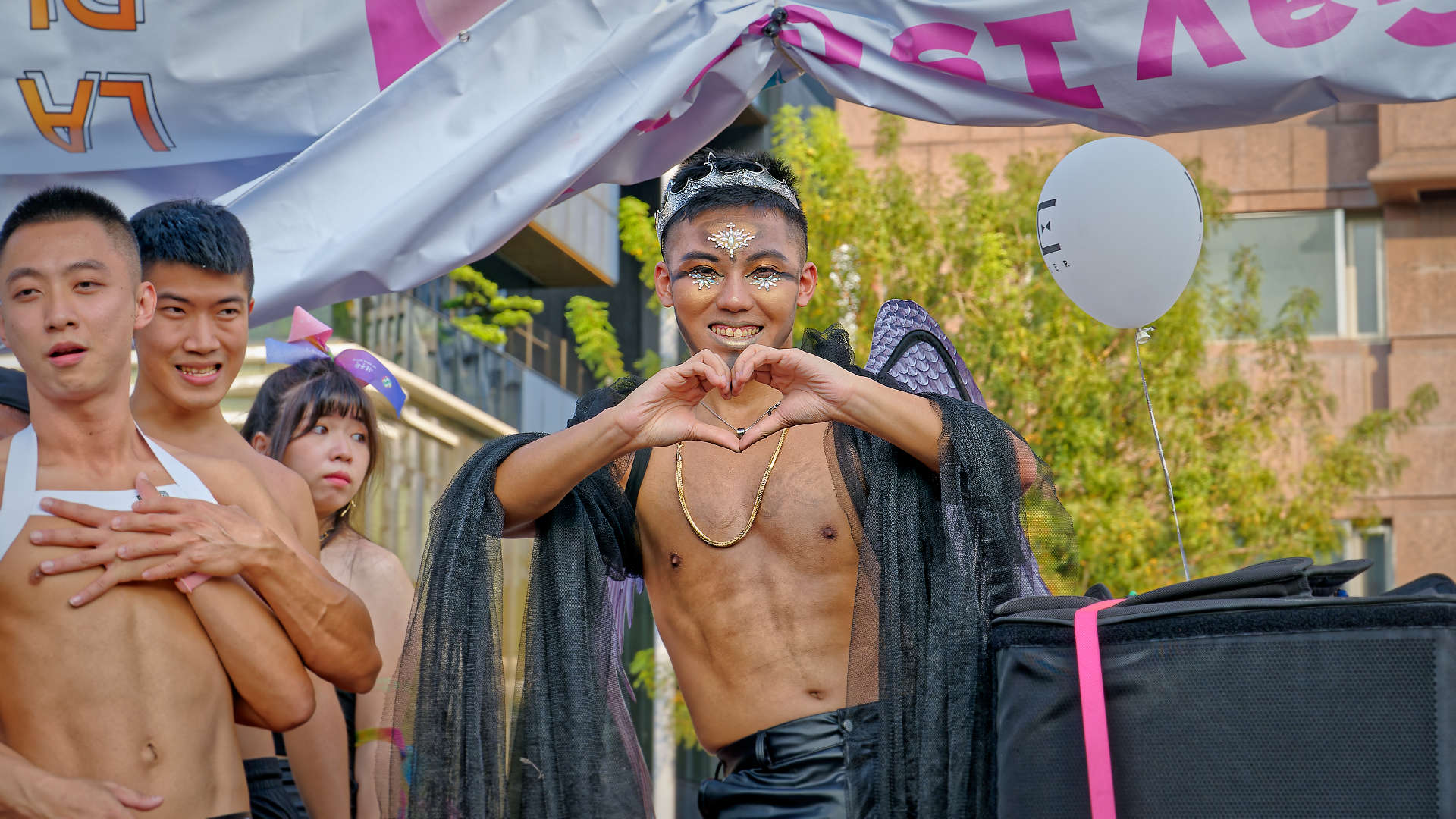 Shirtless dancer looking at the camera and making a heart-shape with his hands.