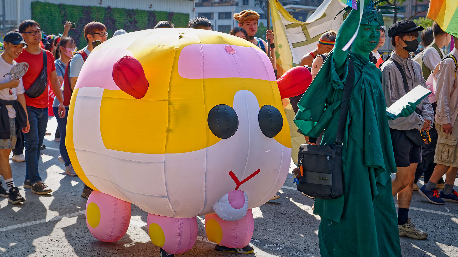 Person dressed as the Statue of Liberty, and a person inside an inflatable animal costume, at the Kaohsiung Pride parade.