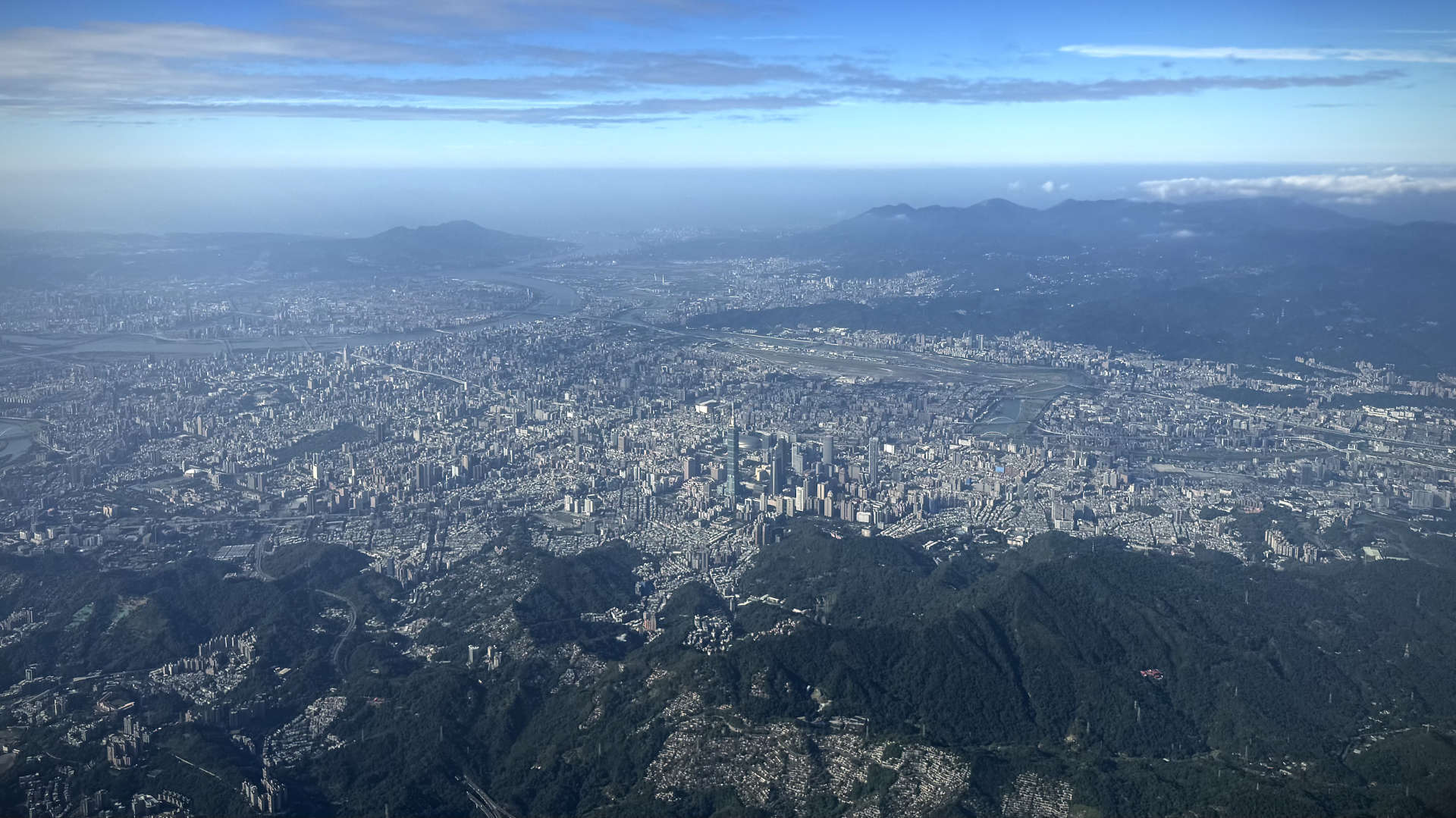 Aerial view of Taipei, with Taipei 101 in the center and Songshan Airport beyond.