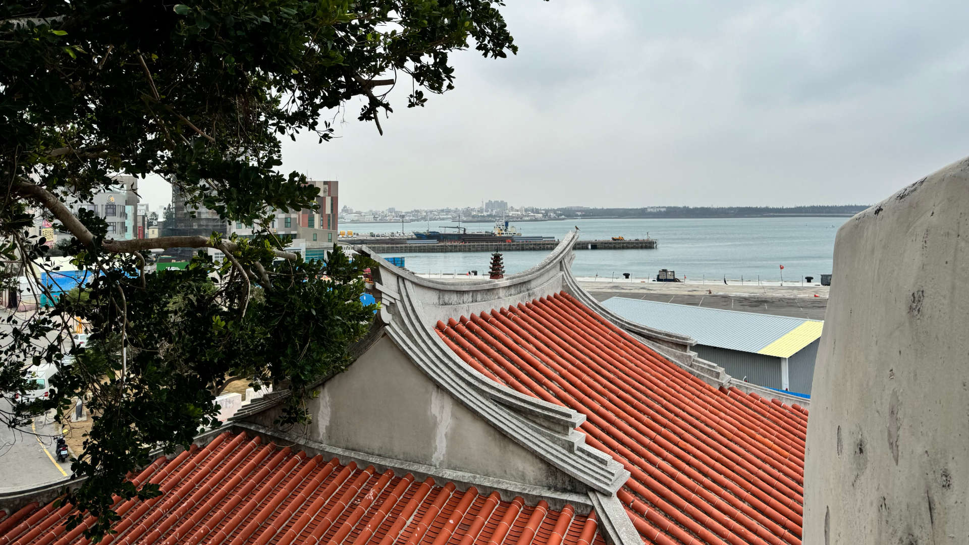 Magong Harbor from across a traditional tiled rooftop.