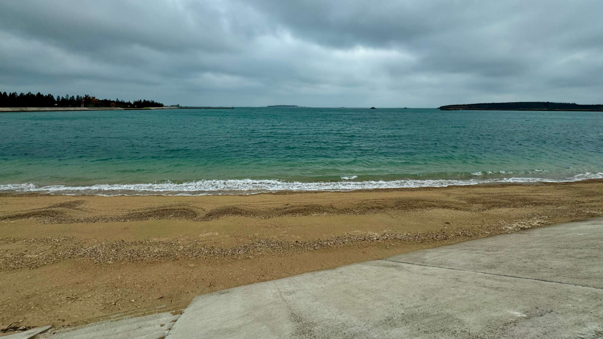 A golden sandy beach and calm turquoise water beyond.