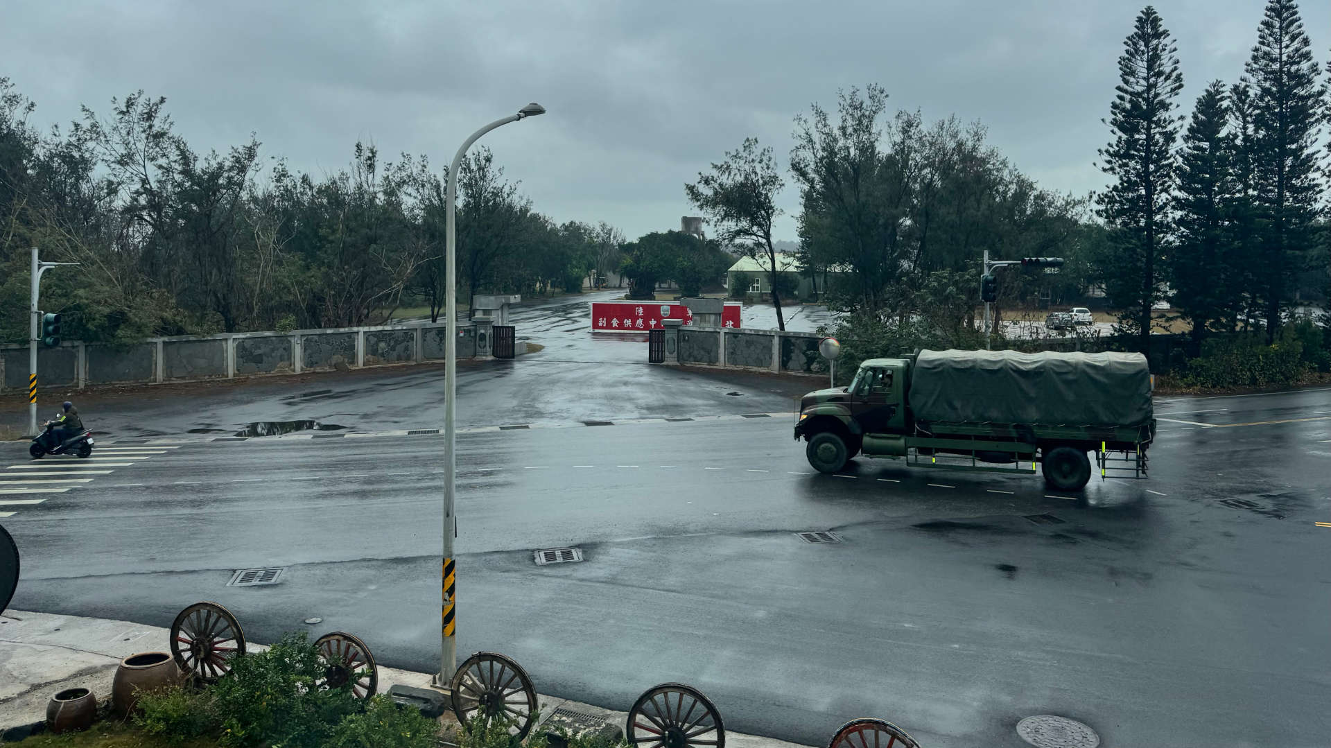 An army vehicle drives past the entrance to a military facility.