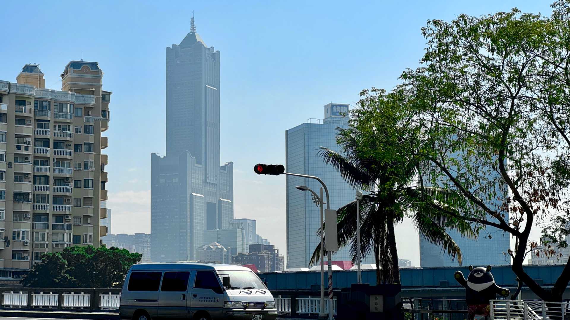 85 Sky Tower, an unconventional 85-floor skyscraper with a hollow central core, viewed in the distance across a bridge over Love River, Kaohsiung.