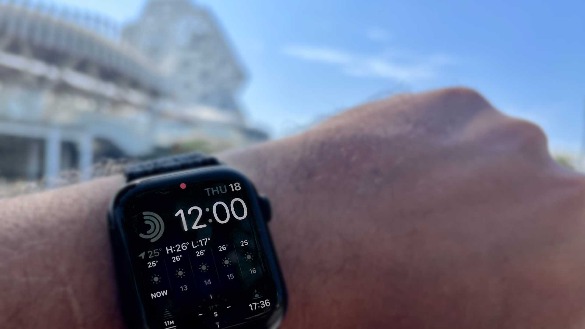 Close-up of an Apple Watch on a wrist, showing the time is 12 noon and the temperature is 25ºC.