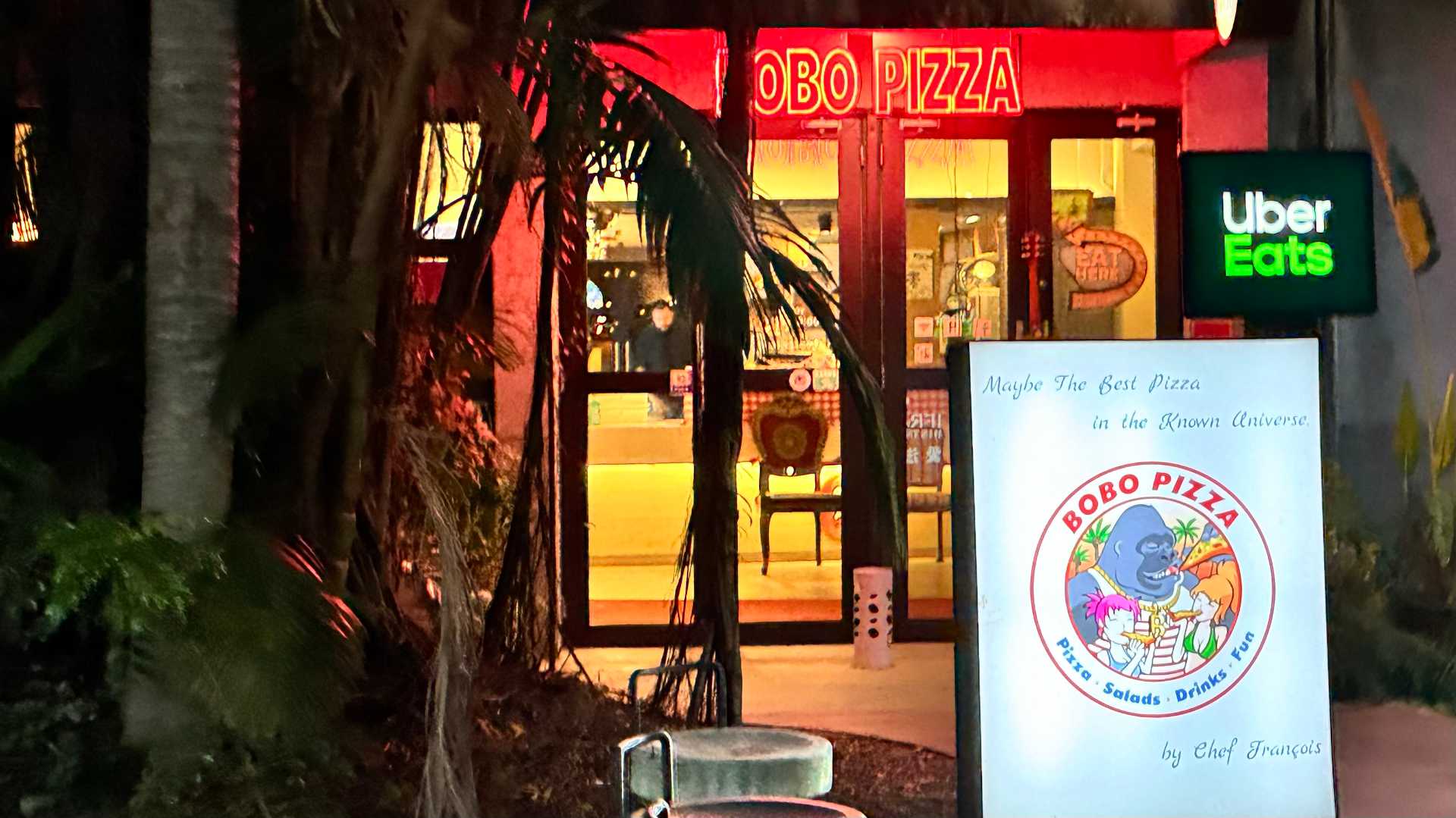 Exterior of Bobo Pizza restaurant. A sign in front says ‘Maybe The Best Pizza in the Known Universe. By Chef François’.