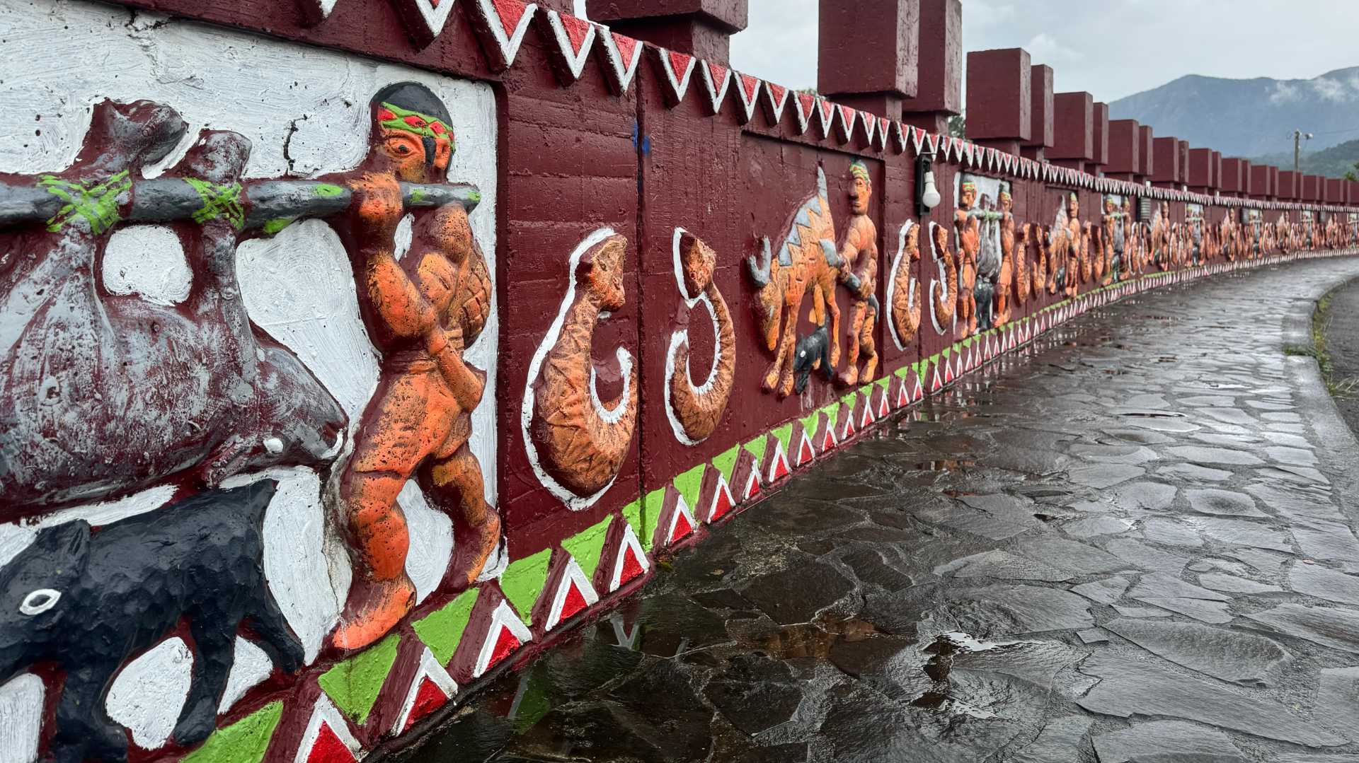 A painted relief on a bridge. The paintings show people carrying dead animals or hunting animals.