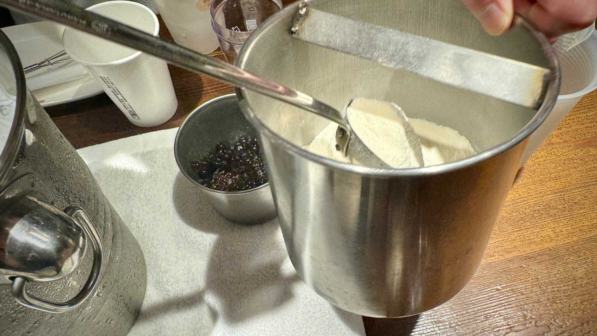 Creamer powder being scooped out of a metal container.